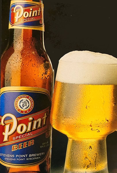 A retro bottle of Point Special beer next to a foaming glass of golden beer.